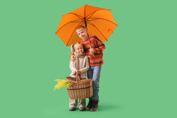 Children with umbrella and picnic basket on green background