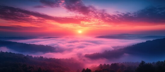 Obraz premium Vibrant sunrise over a misty mountain landscape.
