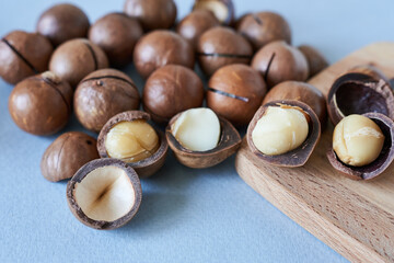 Macadamia nuts on wooden board. Macadamia nuts on blue background