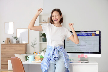 Happy teenage girl with college application form on computer at home