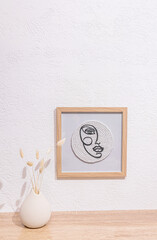 A stylish modern painting on the white surface of a table or chest of drawers with a vase of dried flowers. home decor in white tones. Vertical view.