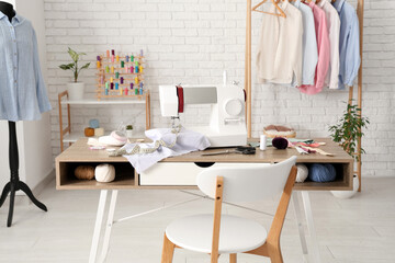 Tailor's workplace with sewing machine, different supplies and mannequin in atelier