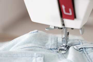 Modern sewing machine with jeans in atelier, closeup