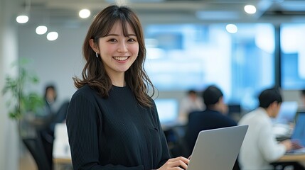 Smiling Japanese businesswoman standing in an office, holding her laptop. She is wearing casual clothes, and other people working behind her are blurred.,generated ai. 

