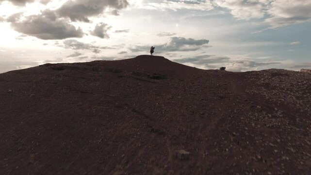 Aerial drone view of a traditional Mongolian eagle hunter on horseback, climbing a hill with the eagle in his arms, spectacular shot with the steppe in the background at sunset