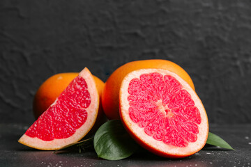 Fresh ripe grapefruits and leaves on black background