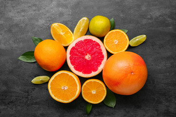 Different citrus fruits and leaves on black background