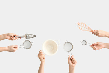 Female hands holding sieves with cake spatula, colander and whisk on white background