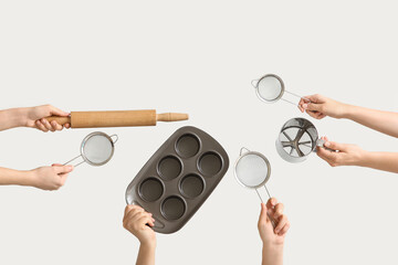 Female hands holding sieves with rolling pin and baking tin on white background