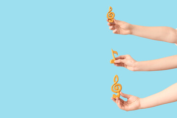 Female hands with music note and treble clefs on blue background