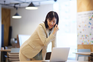 オフィス内でスマートフォンで電話をする日本人女性
