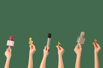 Female hands holding microphones with music notes on dark green background