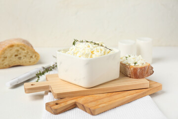 Bowl of fresh cottage cheese with thyme and bread slice on white background