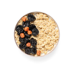 Bowl of tasty oatmeal with prunes and hazelnuts on white background