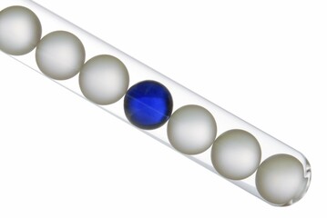 Six white balls and one blue ball in a test tube, symbolic image for being different