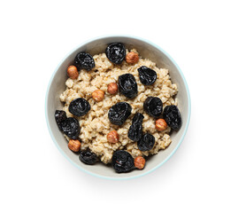 Bowl of tasty oatmeal with prunes and hazelnuts on white background