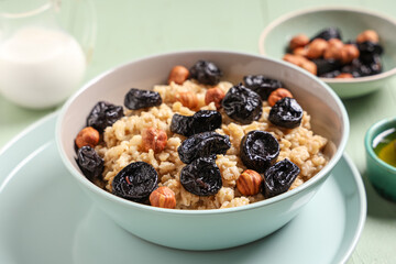 Bowl of tasty oatmeal with prunes and hazelnuts, closeup