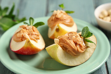 Plate with tasty apple wedges, nut butter and mint leaves, closeup