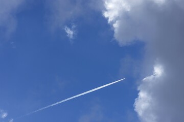 Airplane with condensation stripes in the blue cloud sky, Germany, Europe