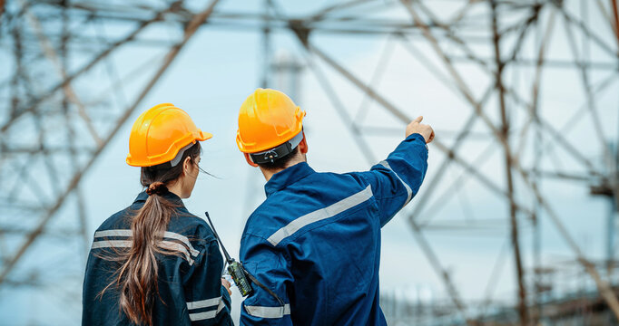 Engineers inspect power lines and discuss safety protocols at electrical substation site during daytime
