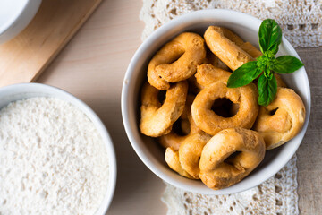 Artisanal homemade typical apulian taralli bowl wooden cutting board, crumbles, baked snack aperitif south italian culture. Flat lay 