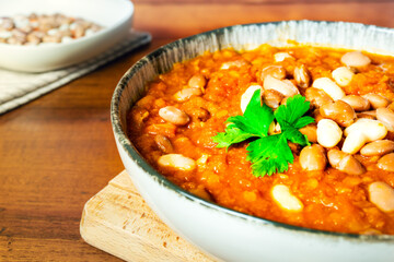 Warm hearty legume soup in rustic ceramic bowl white and borlotti beans fresh parsley. Homely vibe, winter comfort food concepts, vegan vegetarian