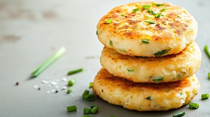 Stack of three golden potato pancakes with chives.