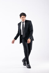 A man in a black suit and tie stands in front of a white background