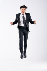 A man in a black suit and tie stands in front of a white background