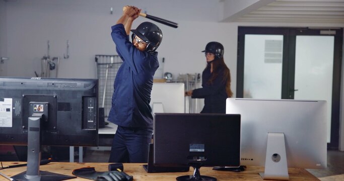 Computer, weapon and friends in rage room for frustrated, anger management and stress relief. Bat, safety gear and violence with people in smash center for demolition break and cathartic therapy