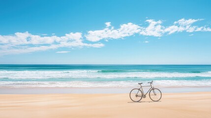 Fototapeta premium A single bicycle parked on soft golden sand with ocean waves in the background, under a bright blue sky.