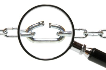 Broken chain link under magnifying glass, symbolic for finding the weak spot
