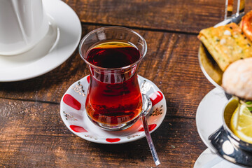 Freshly brewed black Turkish tea with sweetener and lemon slice on wooden table