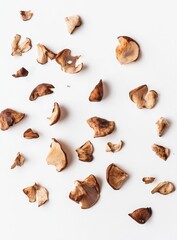 Fototapeta premium Dried shiitake mushroom pieces scattered on white background.