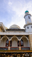 A stunning low-angle shot of a mosque, showing off its unique architectural design against a partly cloudy sky backdrop.
