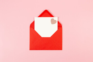 Top view of red envelope, white card on pink background. Valentine's day, pink glitter heart, love. Post flat lay, copy space.