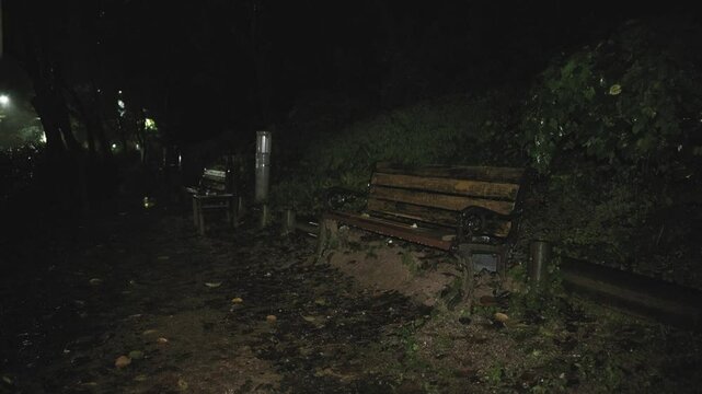 Rain falling on a bench in the park on a quiet night