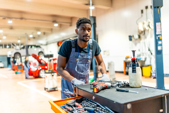 Car mechanic pushing a tool trolley in a busy workshop