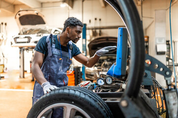 Mechanic changing car tire and using computer in auto repair shop