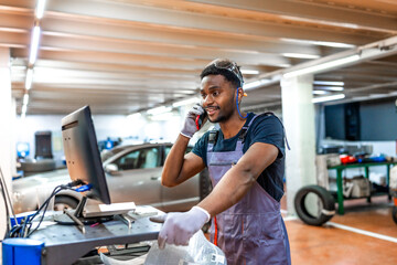 Mechanic using computer and talking on phone in auto repair shop