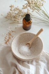 A small bowl of salt and a bottle of oil are on a table. The bowl is filled with salt and a spoon is in it. The scene is simple and peaceful, with the salt