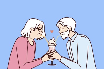Elderly romantic couple drinking cocktail from straws together enjoying retirement and dating on eve of february 14th Valentine day. Romantic grandparents show love between elderly