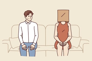 Indecisive man sits near woman with paper bag on head and is afraid of becoming acquainted. Indecisive guy sits on sofa with girlfriend, and is stressed due to timidity interfering with relationships