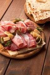 Tagliere con prosciutto crudo, prosciutto cotto, mortadella e parmigiano, prodotti tipici italiani, antipasti europei 