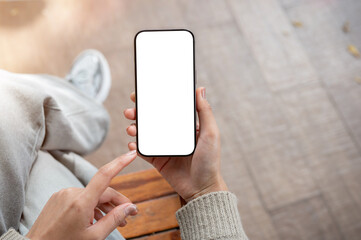 Top view of a woman uses her phone while sitting indoors. the smartphone with a white screen mockup