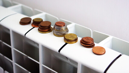 Rising cost of energy and bills concept. Coins on a home radiator heater. Energy and Cost of living crisis