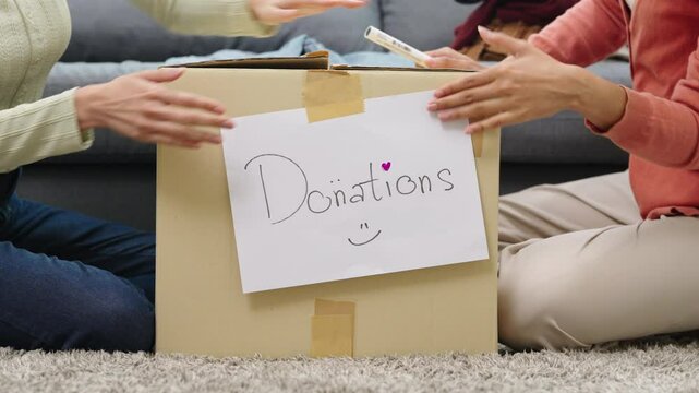 close up group of asian young adults sorting and packing clothes into donation box. community support, and charitable giving