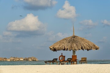 Parasol, sunbeds and a lifebuoy on the beach, water bungalows at the back, Paradise Island, Maldives, Asia