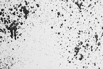 gray background, photograph of black paint splashes on white wall