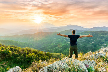 Obraz premium happy man watching amazing highland evening sunset, person delight with nature landscape